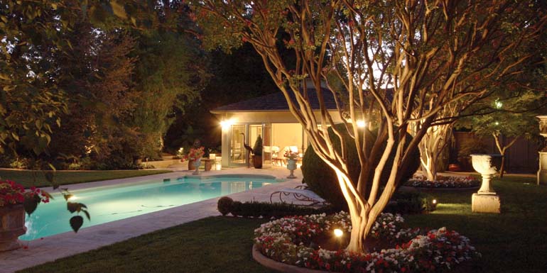 Two lounge chairs over look an inviting pool and a pool house