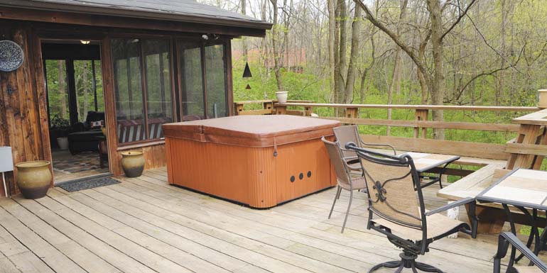 Hot Tub In The Woods - A large deck in the woods with a hot tub outside the lanai.