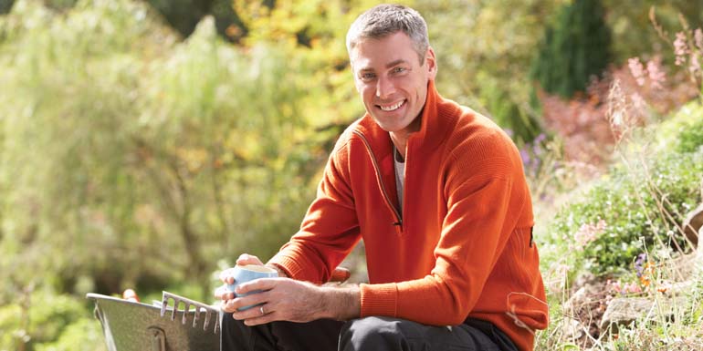 Man Having Coffee Break Whilst Working Outdoors In Garden