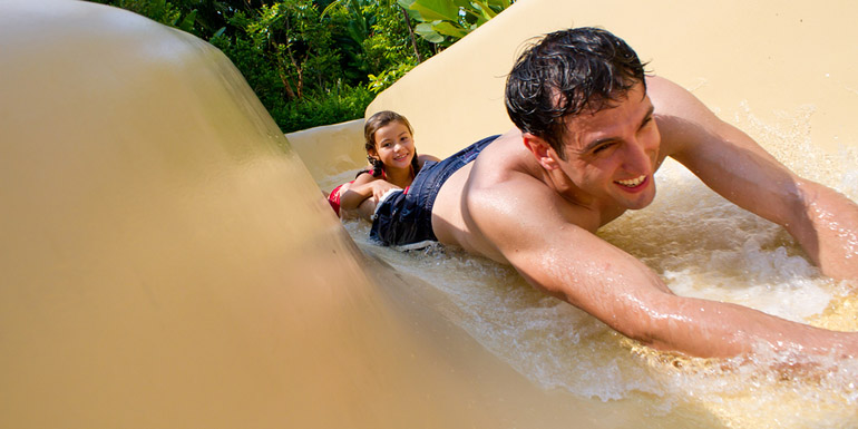 Father and Daughter Sliding Down Water Slide