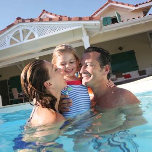 Family playing in swimming pool of private villa