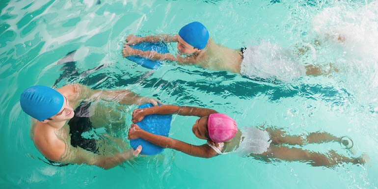 Cute swimming class in pool with coach at the leisure center