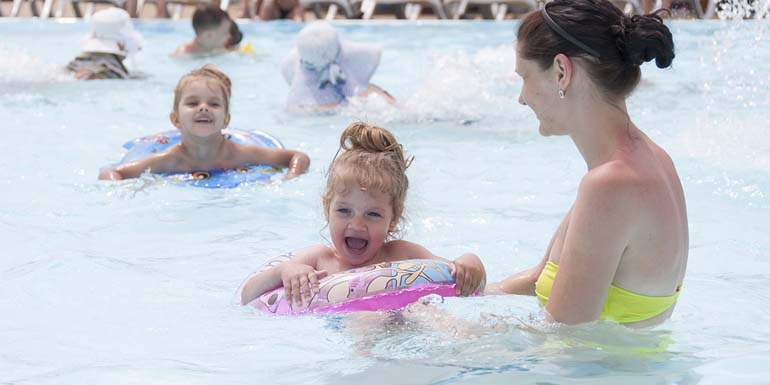 A mother and two daughters are swimming in a public pool