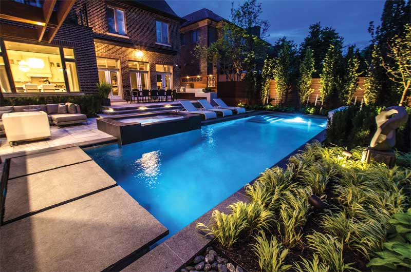 Backyard landscape, pool, and spa illuminated