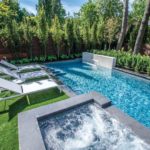 The pool includes a raised water feature and raised, attached concrete hot tub.