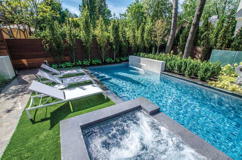 The pool includes a raised water feature and raised, attached concrete hot tub.