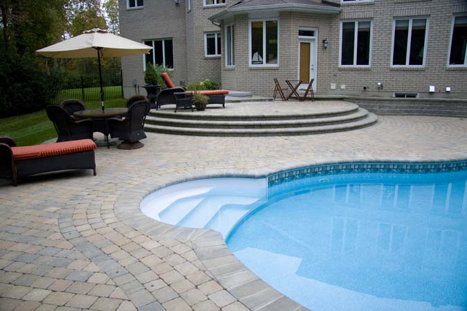 Poolside interlock concrete paver patio and raised terrace.