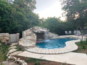 A backyard pool with decorative artificial rocks with a real look and feel.