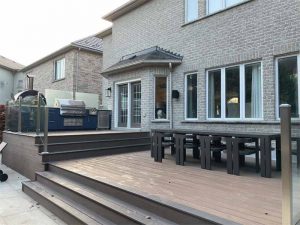 A tiered deck with an elevated outdoor kitchen, adjacent to the house, and a lower dining area eliminated the potential for a set of stairs protruding into the yard.