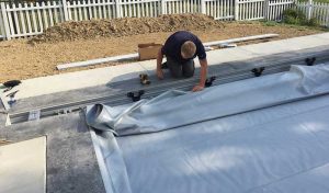 A man installing an auto cover on a pool.