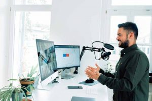 A man creating content for social media, speaking in a microphone, while interacting with an audience on a monitor.