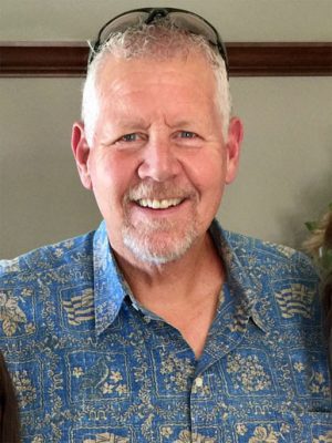 headshot of a man in a blue shirt smiling