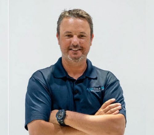 man with crossed arms smiling at camera