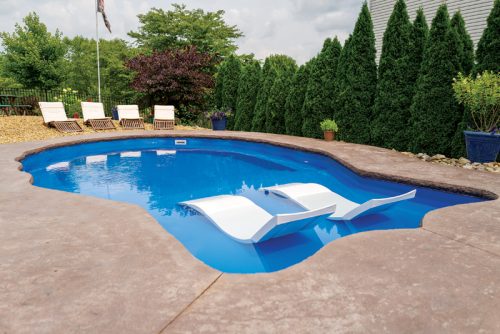 A serene swimming pool with white loungers, surrounded by lush greenery and decorative plants.