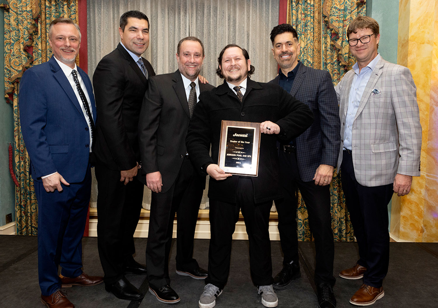 Group of six men posing with a plaque. The person in the center is holding the Journeyman Dealer of the Year Award