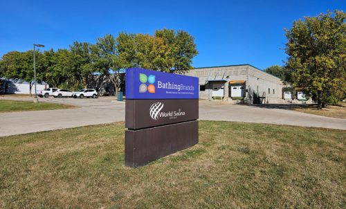 Sign for Bathing Brands, showcasing the company name and logo, with a warehouse building in the background.