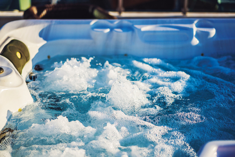 Close-up of a bubbling hot tub with water jets creating a relaxing hydromassage experience.