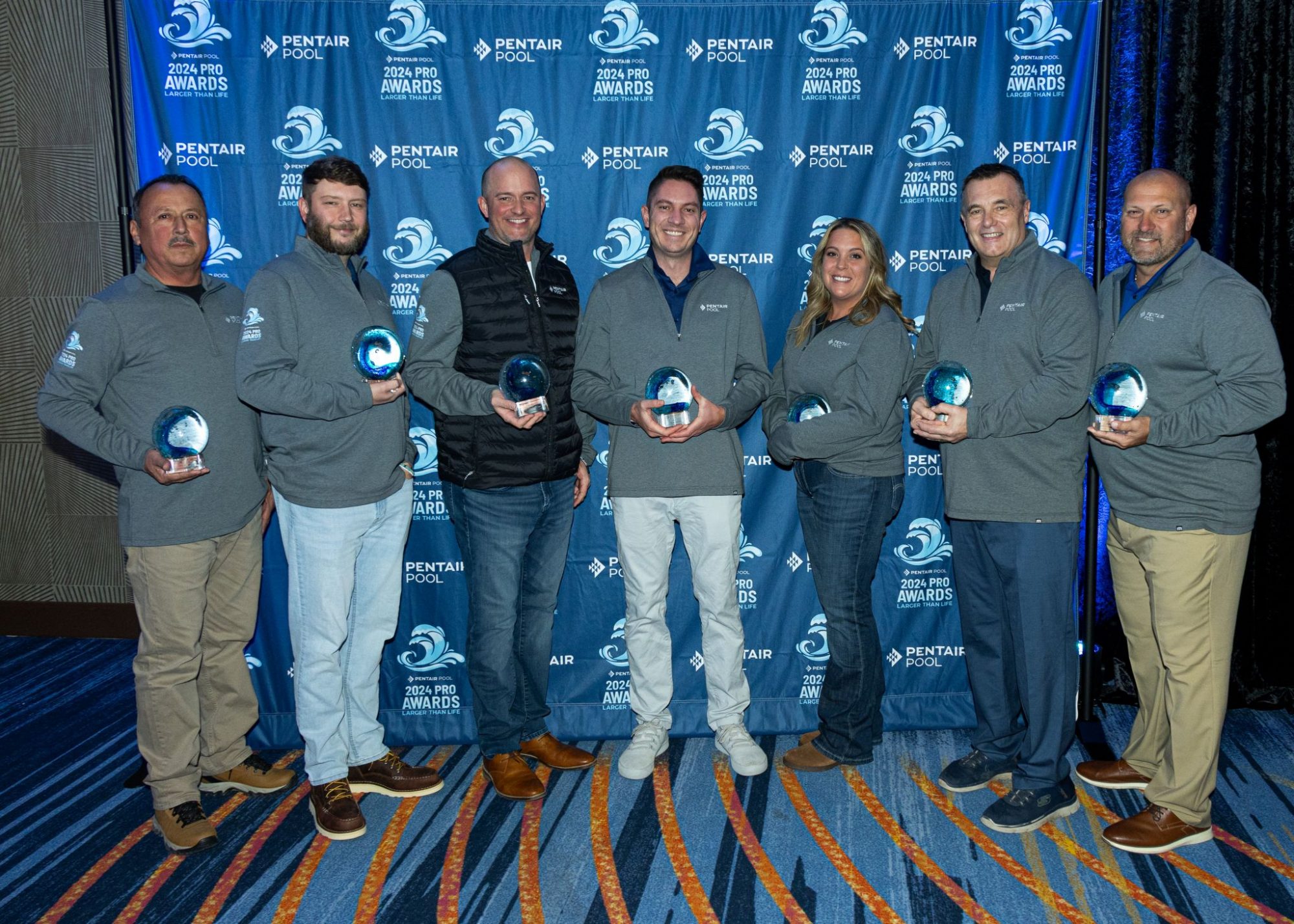 Group of people holding awards in front of a Pentair Pool banner.